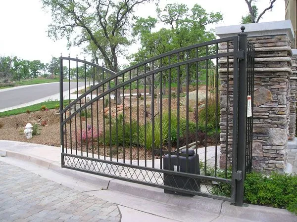 A wrought iron gate is open in front of a stone wall