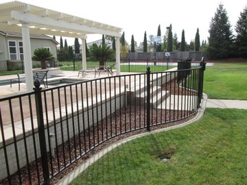 A black wrought iron fence surrounds a swimming pool